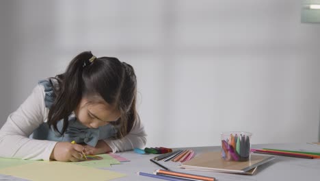 Studioaufnahme-Eines-Jungen-Mädchens-Am-Tisch,-Das-In-Bild-1-Zeichnet-Und-Malt