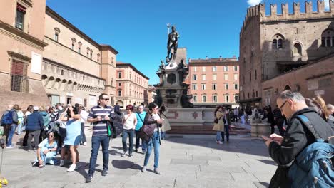 people gathered around the fountain of neptune in bologna, italy