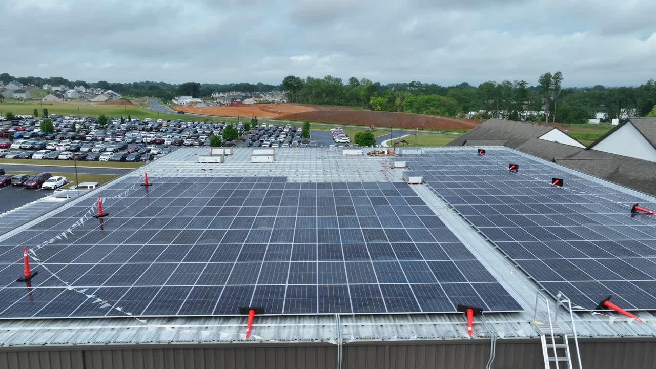 paneles solares en un techo de almacén con un estacionamiento y construcción en el fondo