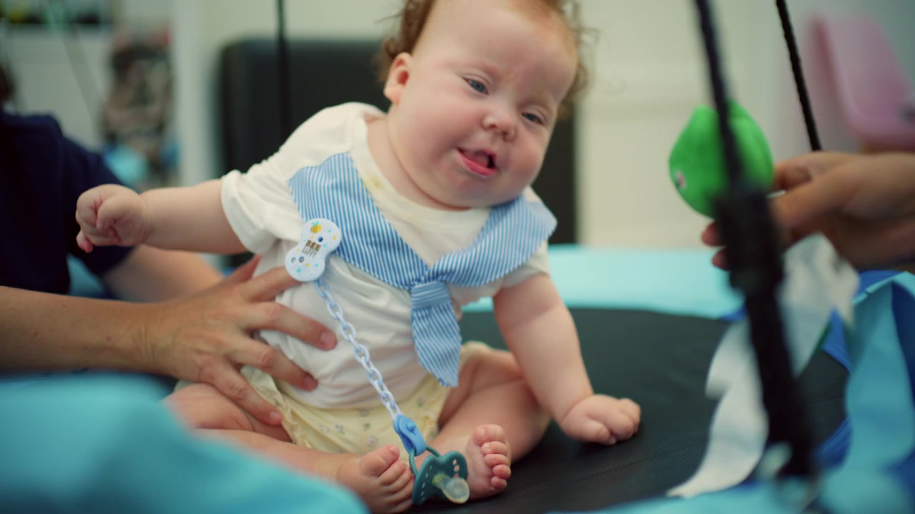 Baby with down syndrome getting professional help with physical therapy, promoting child development and rehabilitation in a medical clinic