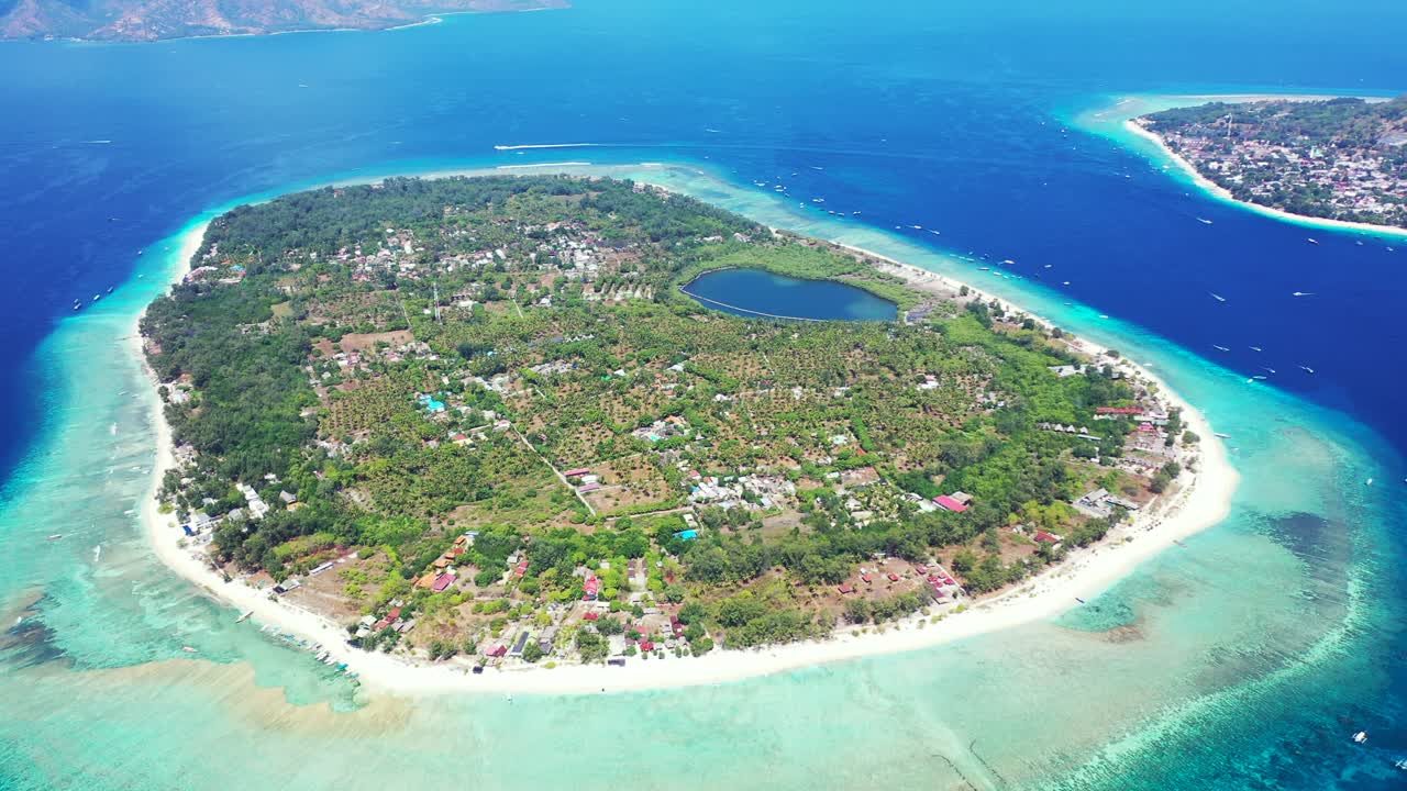 무성한 초목, 리조트, 산호초 장벽이 있는 청록색 석호로 둘러싸인 백사장이 있는 인도네시아 저지대 열대 섬