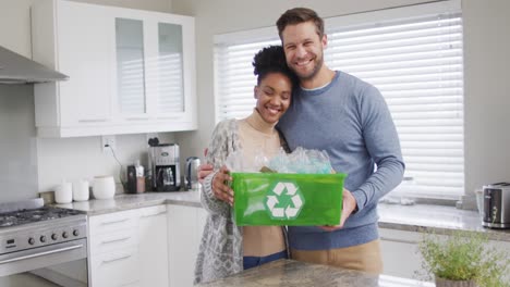 video de una feliz pareja diversa abrazando y sosteniendo un contenedor de reciclaje con botellas de plástico