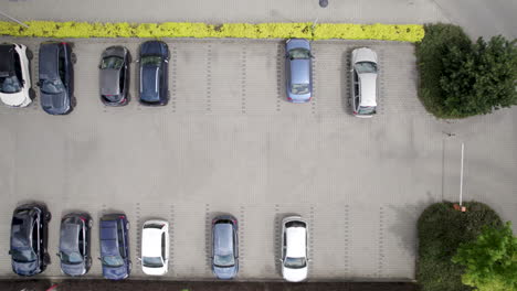 Aerial-view,-captured-from-above,-showcases-a-bustling-car-park-brimming-with-vehicles-in-the-heart-of-a-quaint-European-city---4K