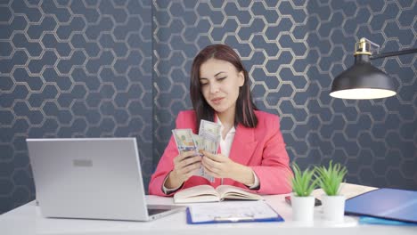 Young-business-woman-counting-money-looking-at-camera.