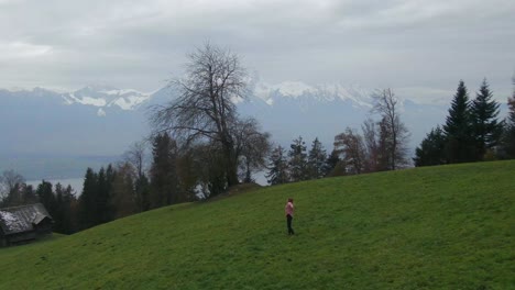 cinematic aerial drone beautiful woman dancing swiss alps countryside dance jump in the fog hillside sounds of music scene thun bern interlocken switzerland mountainside circling slowly right movement