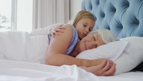 Affectionate-granddaughter-kissing-grandmother-in-bedroom-4k