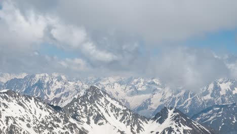 air flight through mountain clouds over beautiful snow-capped peaks of mountains and glaciers.