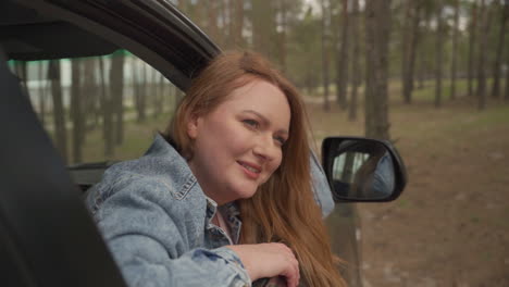 Red-Haired-Female-Enjoys-A-Drive-Through-The-Countryside-From-The-Window-Of-The-Car