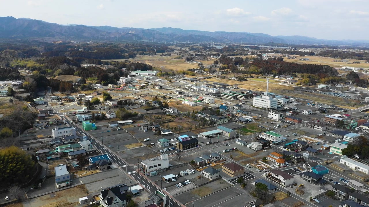 Aerial view of buildings and distant mountains in Tomioka, Japan.