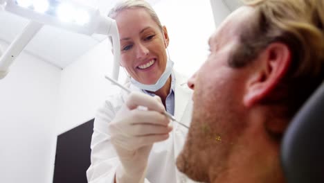 una dentista examinando a un paciente con herramientas dentales