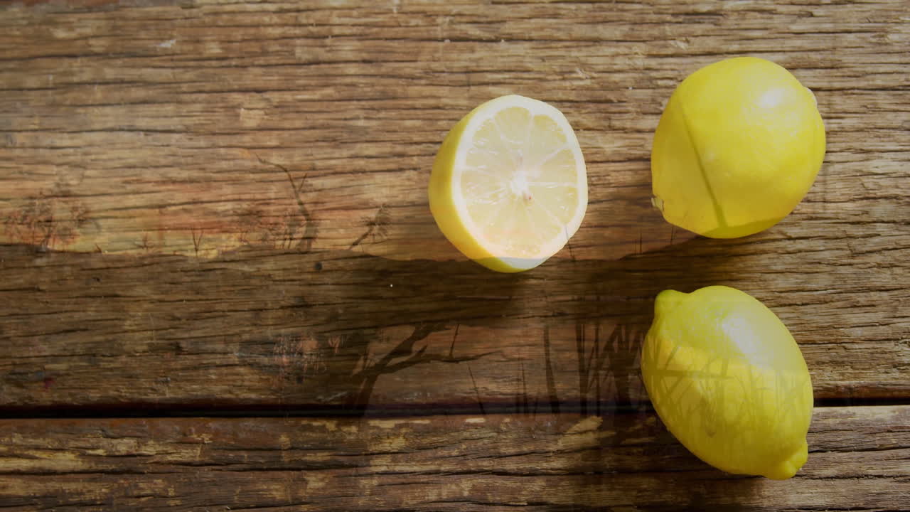 Lemons and lemon half casting soft shadows on rustic wooden surface