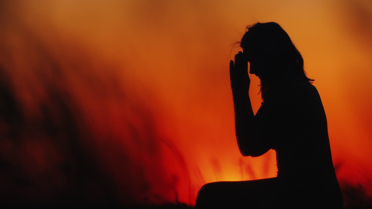 una mujer de mediana edad reza al atardecer hierba alta balanceándose en primer plano