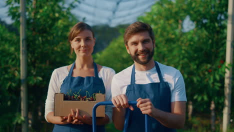 Farmers-team-looking-camera-holding-cherry-berry-crop-in-sunny-garden-plantation