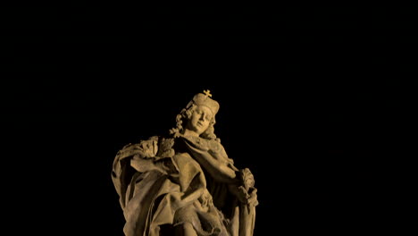 stone statue of a female saint in a cloak at night,prague,czechia