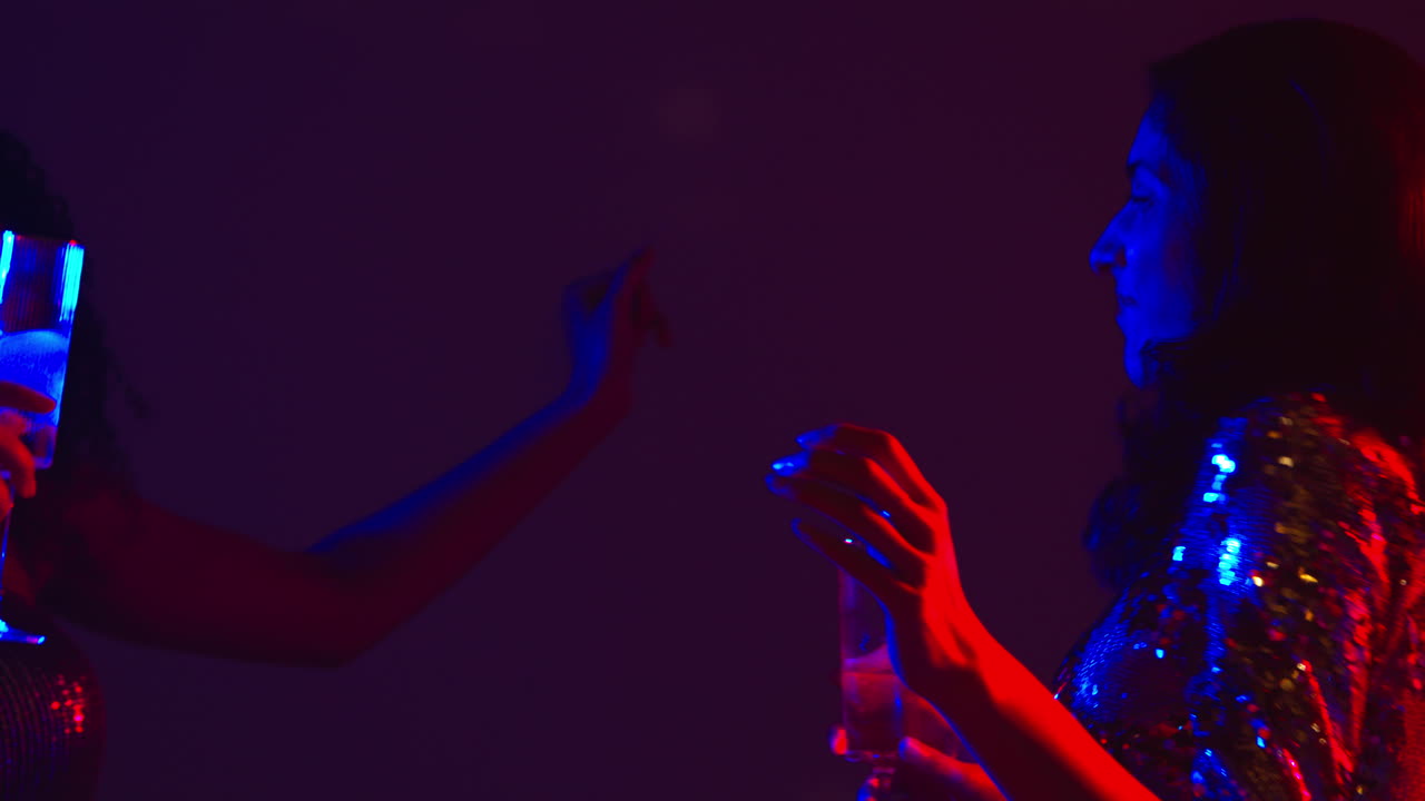 cerca de dos mujeres en un bar de club nocturno o discoteca bailando y bebiendo alcohol 1