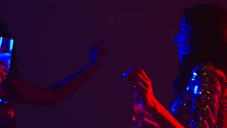 close up of two women in nightclub bar or disco dancing and drinking alcohol 1