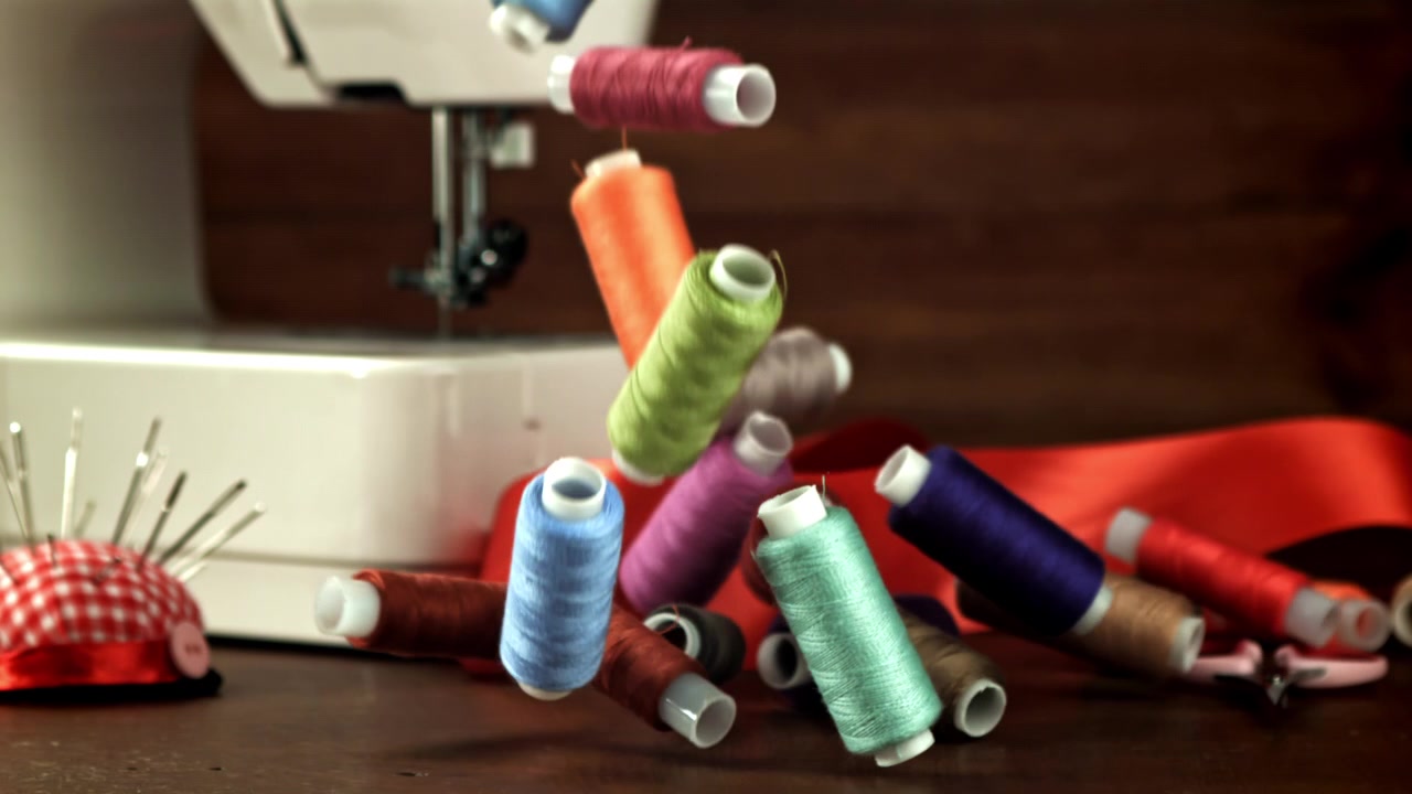 Colorful Spools of Thread Falling in Slow Motion onto a Sewing Table