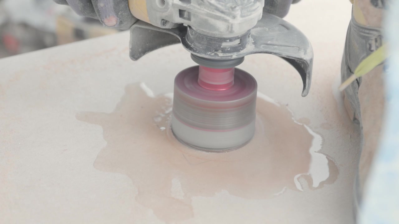 Close up of a water cutting with a circular power tool. Tiler cutting holes in tiles.