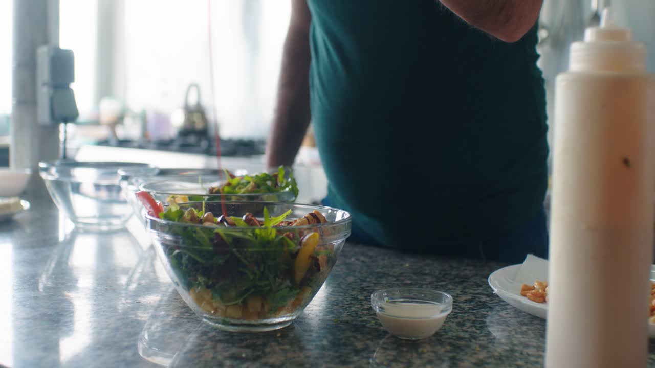 The cook is adding the sauce on the salad