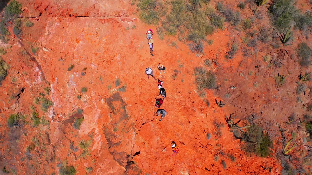 gente haciendo rappel en una montaña roja junto al mar