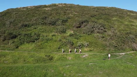 grupo de amigos caminando en fila por una colina verde