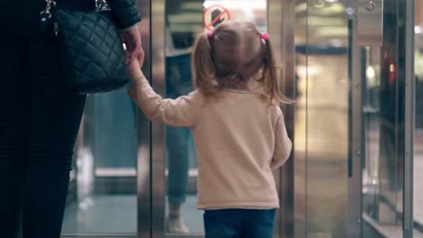 CU-4k-Young-mother-leads-her-daughter-by-the-hand-along-the-business-center-enter-elevator