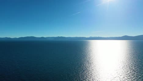 glistening water with sunlight reflection at lake tahoe in california, usa and mountains in the background