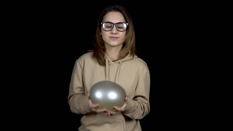 una mujer joven lanza bolas con agua. la niña sacude la pelota sobre un fondo negro. el globo tiembla como jalea.