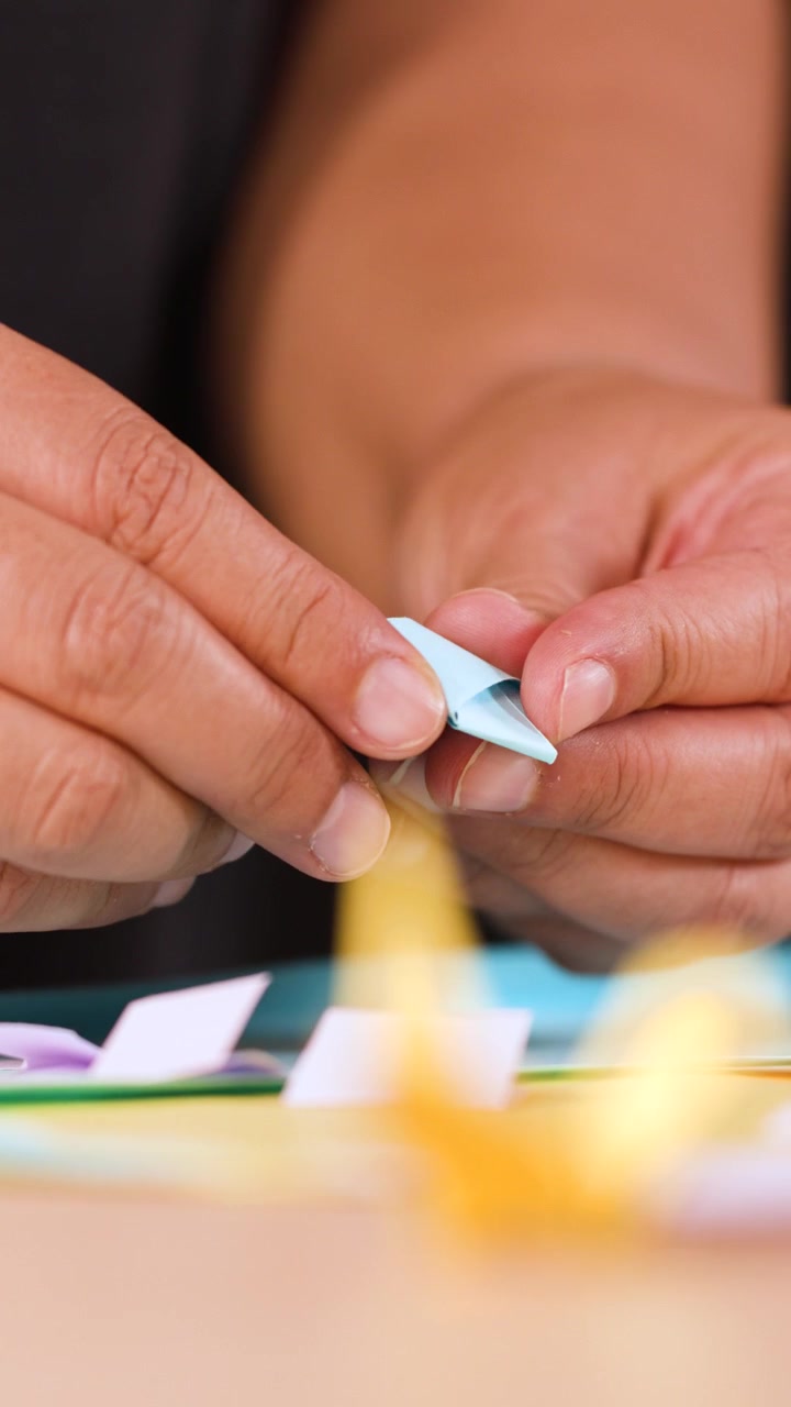 Primo piano di mani che usano le forbici e piegano carta blu per un progetto di origami