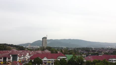 Slow-shot-flying-straight-surrounded-by-houses-and-trees-with-a-high-construction-building-in-sight-before-the-valley-beyond