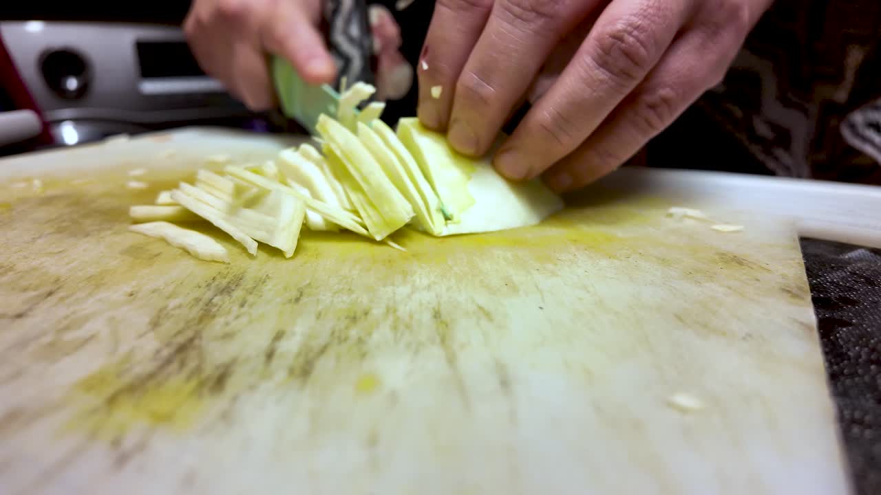Primo piano di mani che tagliano il cavolo su un tagliere in cucina da un’angolazione bassa per progetti di cucina, preparazione alimentare e arte culinaria