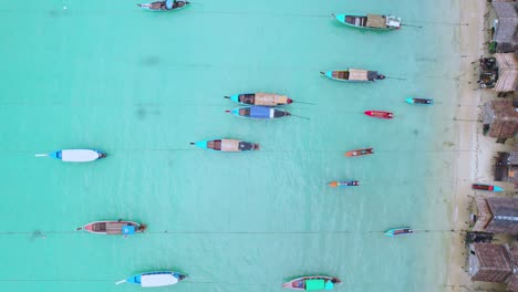 Barcos-De-Cola-Larga-Con-Una-Toma-Panorámica-Aérea-De-Arriba-Hacia-Abajo-Para-Revelar-Cabañas-De-Madera-A-Lo-Largo-De-Una-Playa-En-Tailandia