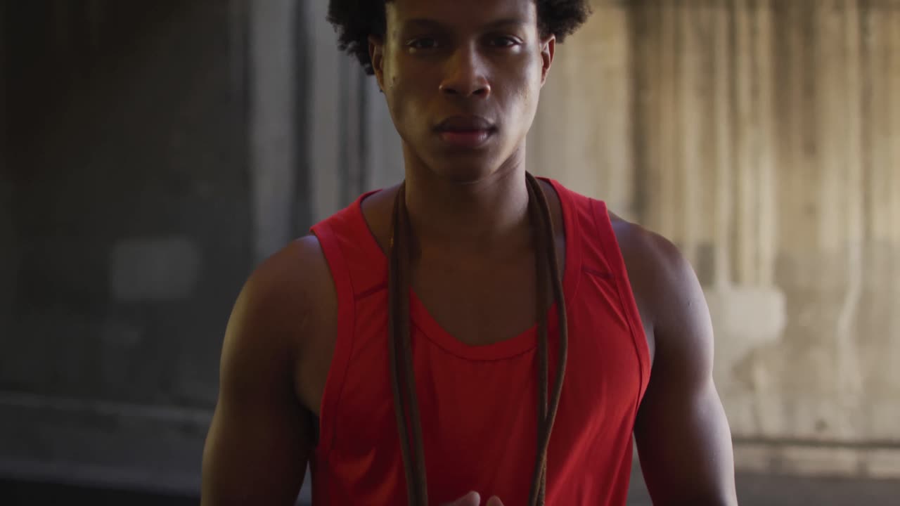 Portrait of fit african american man exercising in city, standing with skipping rope around neck