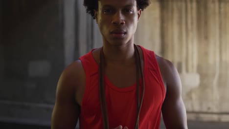 portrait of fit african american man exercising in city, standing with skipping rope around neck