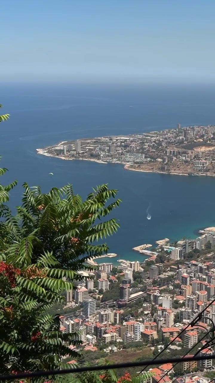 Vista aerea di una città costiera con mare blu, edifici moderni e una costa panoramica, inquadratura ravvicinata.