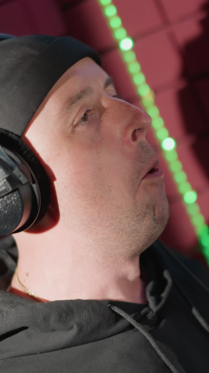 un hombre vestido de negro, cantando apasionadamente en un micrófono en una sala de grabación a prueba de sonido. su rostro muestra una expresión intensa y enfoque, completamente inmerso en la actuación