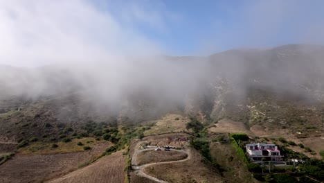 disparo aéreo volando a través de nubes de niebla bajas con paisaje de montaña en el fondo en malibu