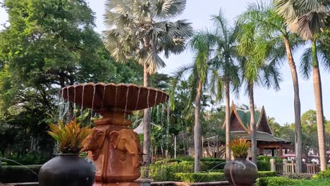 a beautiful fountain surrounded by lush palm trees and vibrant greenery in a tropical setting.