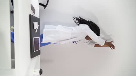 black female doctor in medical uniform dancing in clinic