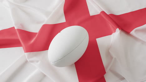 pelota blanca de rugby sobre la bandera de inglaterra con espacio de copia, en cámara lenta
