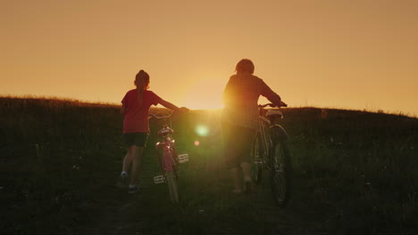 an elderly lady walks with her granddaughter bicycles at sunset 1