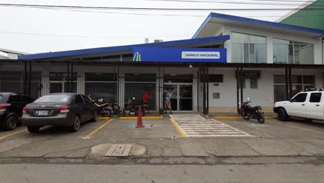 local people wait in front of the fenced entrance area of the national bank of costa rica in puerto viejo.