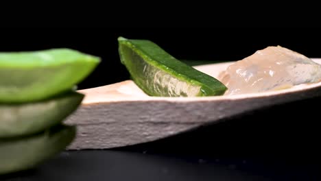 검정색 배경에 얇게 썬 신선한 알로에 베라, 화장품 및 스킨케어 제품 프레젠테이션을 위한 녹색 허브 개념, 둥근 부드러운 동작