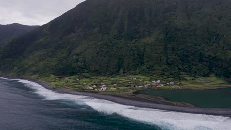 coastal-rural-village,-a-church,-a-lagoon,-with-lush-green-cliffs-landscape,-Fajã-de-Santo-Cristo,-São-Jorge-island,-the-Azores,-Portugal