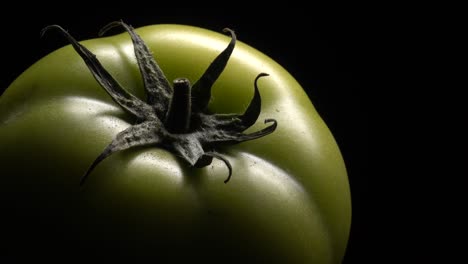 green tomato in rotation on black background.