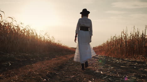 farmer in a dress and hat walks in a field of ripe corn 3