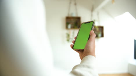 Un-Hombre-Que-Sostiene-Un-Teléfono-Inteligente-Con-Pantalla-Verde-En-Vertical-En-El-Fondo-Blanco-De-La-Casa