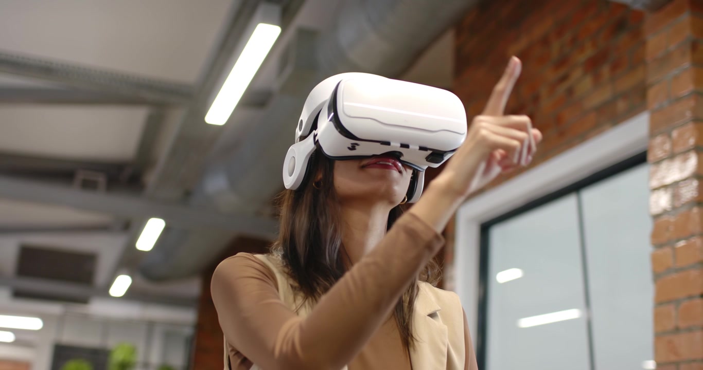 Donna afroamericana con visore VR bianco che, dopo un segnale virtuale, indica e seleziona un menu in ufficio
