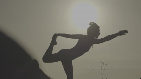 woman practicing yoga outdoors at sunrise/sunset