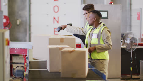 diverse male workers wearing safety suits and scanning boxes in warehouse